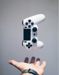 video game controller suspended above a person's open palm